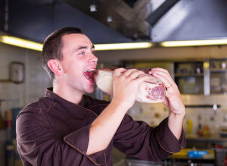 Chef eating a big piese of raw meatの写真素材