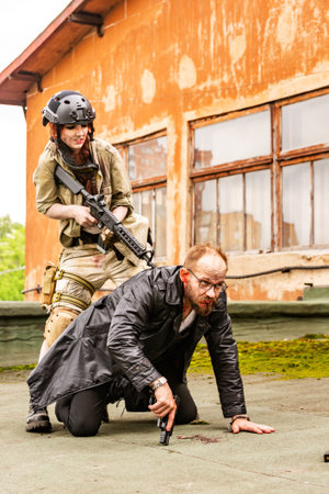 Woman soldier, spy agent killer or police woman with a gun in her hand holding at gunpoint a man...