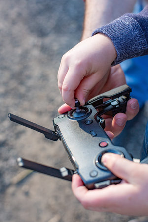 Hands of Father and son holding remote control joystick and piloting quadrocopter