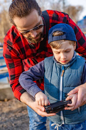 Father and son holding remote control joystick and piloting quadrocopterの写真素材
