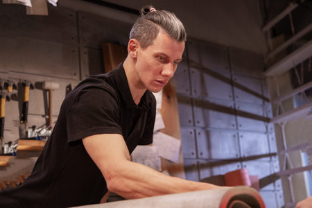 Carpenter doing his job in carpentry workshop. a man in a carpentry workshop measures and cuts laminateの写真素材