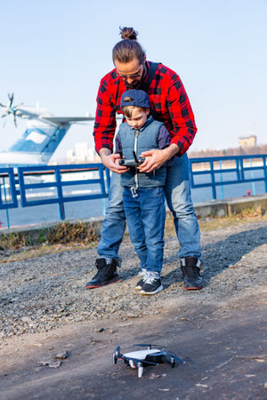 Father and son holding remote control joystick and piloting quadrocopter