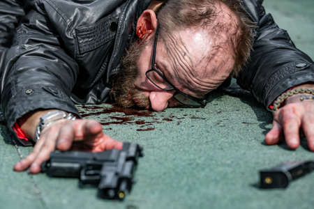 man in blood, he pulls his hand towards the gunの写真素材