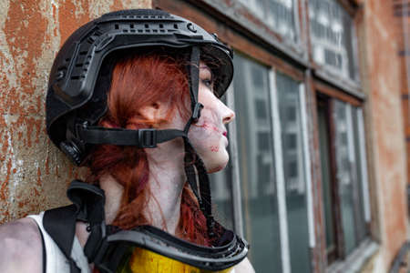 portrait of army girl with rifle in camouflage clothes in urban scene, in hidingの写真素材