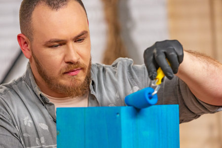 profession, carpentry, woodwork and people concept - carpenter working with wood plank and covers it...