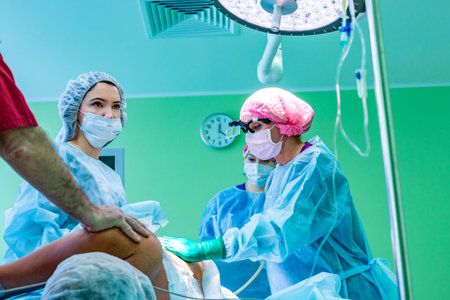 cosmetic liposuction surgery in actual operating room setting showing surgeons group during operationの写真素材