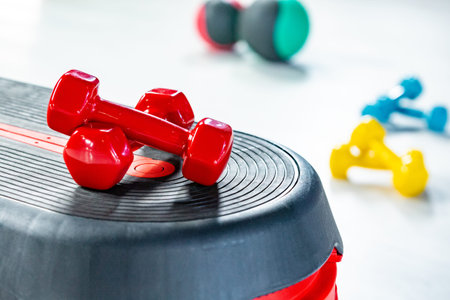 Red modern dumbbells in the foreground on a step platform