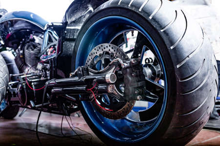 Cropped close up shot of beautiful and custom made motorcycle in the workshopの写真素材