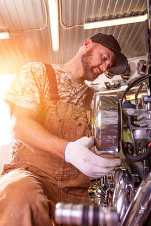 Side view portrait of man working in garage repairing motorcycleの写真素材