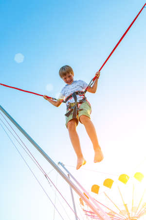 Smilling excited boy jumping on a trampoline with insurance.の写真素材