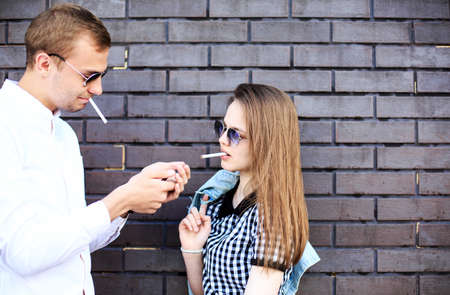 Beautiful girl and handsome guy smoking cigaretteの写真素材