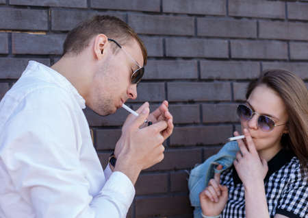 Beautiful girl and handsome guy smoking cigaretteの写真素材