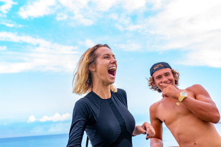 Smiling young active couple surfers relaxing on the beach after sport