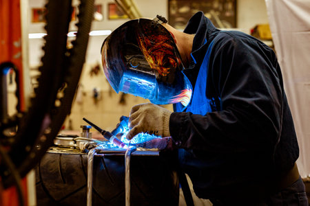 Professional car mechanic working in auto repair service on argon gas cutting machine