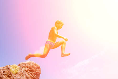 A boy is jumping from the cliff into the sea on a hot summer day. Holidays on the beach. The concept of active tourism and recreationの写真素材