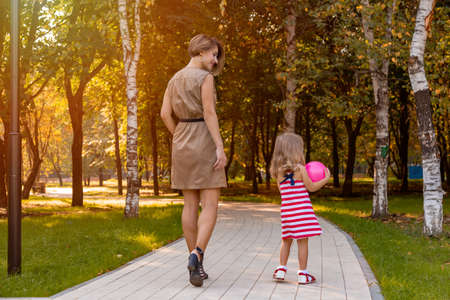 Lovely young mom and daughter in warm sunny summer day. Happy family mother and child little daughter playing and walking in the Park and enjoying the beautiful nature.の写真素材