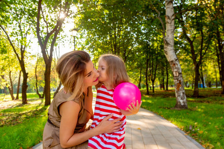 Lovely young mom and daughter in warm sunny summer day. Happy family mother and child little daughter playing and walking in the Park and enjoying the beautiful nature.の写真素材