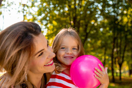 Lovely young mom and daughter in warm sunny summer day. Happy family mother and child little daughter playing and walking in the Park and enjoying the beautiful nature.の写真素材