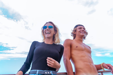 Smiling young active couple surfers having fun on the beach after sport. Beautiful seascape on the...