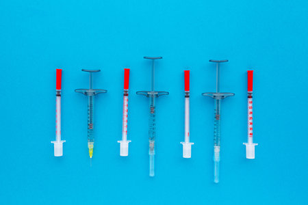 Syringes organized in a row over blue background, top view. Mock up health care medical background.の写真素材