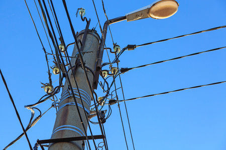 electric wire and lamp on electrical pole with blue cloudy sky background