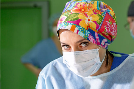 female surgeon doctor wearing protective mask and hat during the operation. Healthcare, medical...
