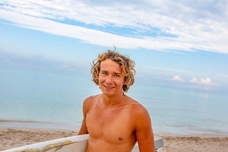 Handsome man walk with white blank surfing board wait for wave to surf spot at sea ocean shore. Concept of sport, fitness, freedom, happiness, new modern life, hipster.の写真素材