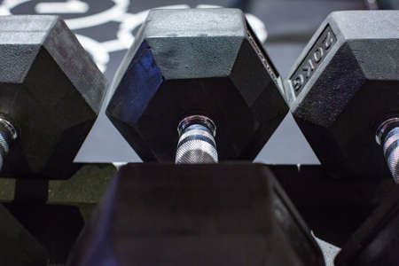 Black rubber dumbbells. Hexagonal heavy duty weight set used for serious hardcore gym workouts, cross fit training and workout routinesの写真素材