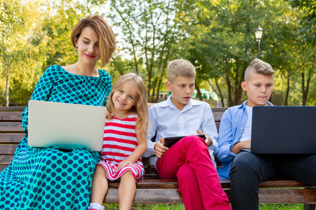 Young family with gadgets sitting on the bench