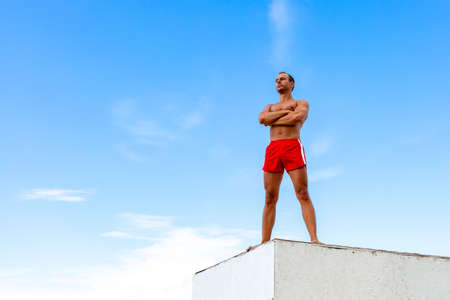 Handsome Athlete Shirtless Young Man stands on a rock against the skyの写真素材