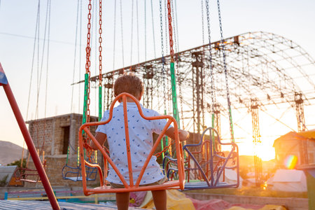 Happy child boy having fun in amusement park. Taking a ride on chain carousel.の写真素材