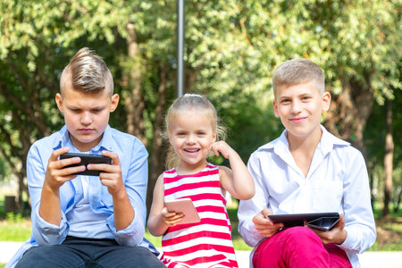 busy kids looking at their phones texting sms and playing sitting outside
