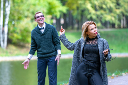 Couple talking seriously outdoors in a park with a green background