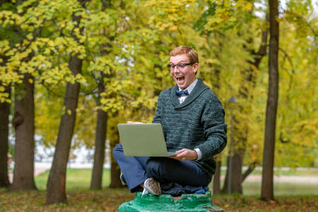A man with lap top on a pedestal who pretends to be a statue in the the autumn park. Get ideaの写真素材
