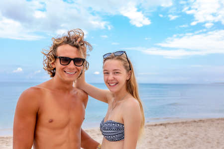 Smiling playful young couple in love having fun at sandy beach.の写真素材