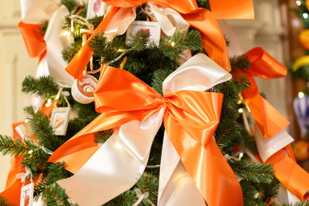 Christmas tree with red balls. Concept New Year celebration background. Closeup photo of christmas tree decorated with white and orange bowsの写真素材