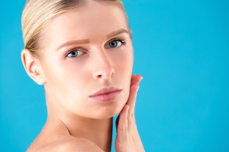 Beautiful Woman Face. Beauty Portrait of young woman blonde on blue background. Perfect Fresh Skin....