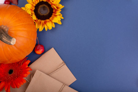 Top view of handcraft gift box with yellow and orange flowers and pumpkins on blue background. Blank...