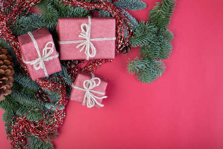 Christmas composition. Christmas red decorations, fir tree branches with toys gift boxes on red background. Flat lay, top view, copy spaceの写真素材
