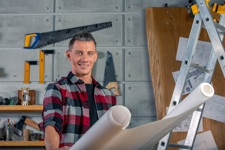 A carpenter works. Carpenter studying drawing project. Against the background of the workshop