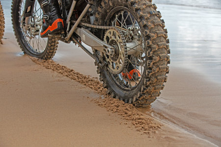 motorcycle wheels leave footprints in the wet sand on the beach