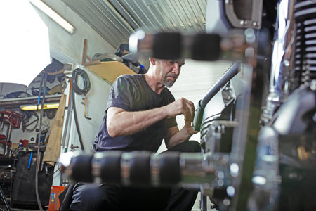 Side view portrait of man working in garage repairing motorcycle