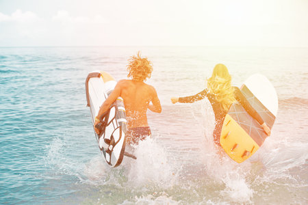 Surfers at the beach- Smiling couple of surfers walking on the beach and having fun in summer....