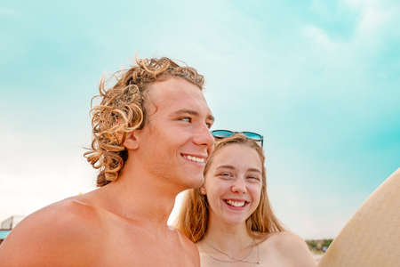 Surfers at the beach- Smiling couple of surfers walking on the beach and having fun in summer. Extreme sport and vacation conceptの写真素材