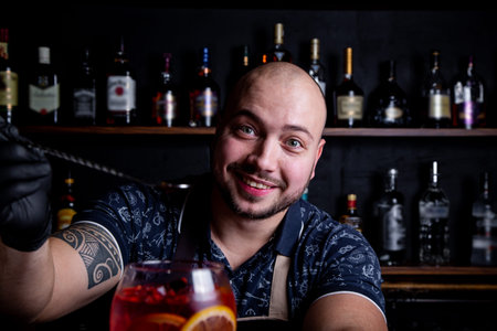 Barman puting to glass of fresh and tasty Aperol syringe cocktail peace of ice