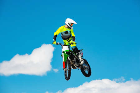 Racer on motorcycle participates in motocross cross-country in flight, jumps and takes off on springboard against sky. Concept active extreme rest.の写真素材