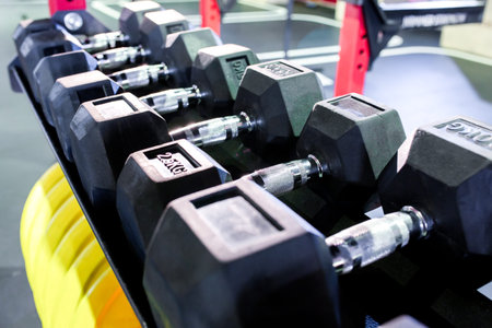Dumbbells, pancakes and weights lying on the shelves. Gym. Equipment for gym