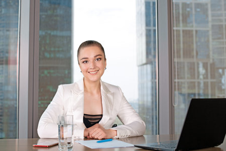 Concentrated at work. Confident young woman in smart casual wear working on laptop while sitting near window in creative officeの写真素材