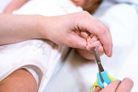 Close up of mother cutting babies nails with scissors. Nursing a child.の写真素材