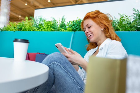 Woman using mobile phone in cafe at shopping mall